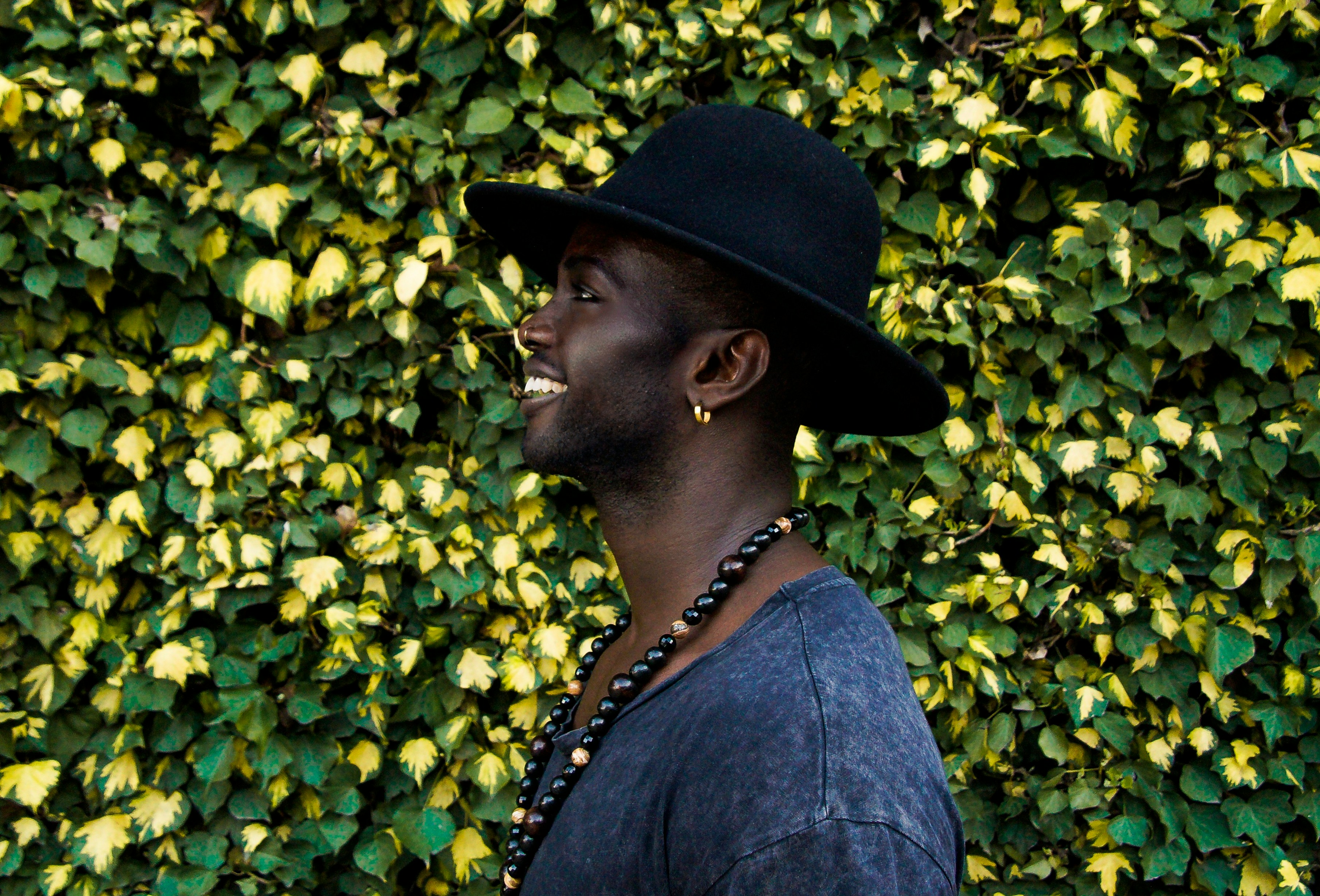Smiling man wearing large brim hat and earring and nose ring
