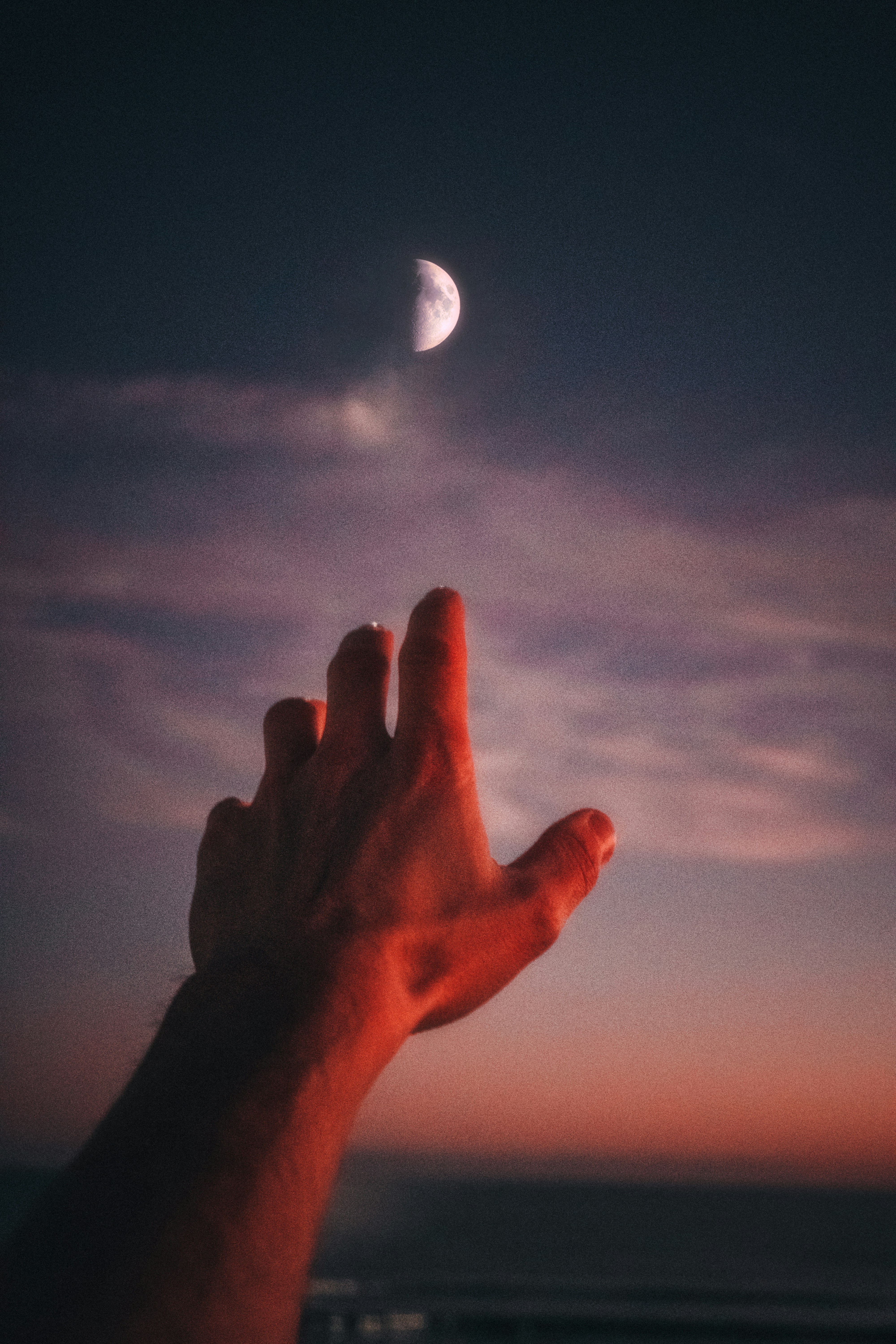 Hand reaching out to the moon at night 